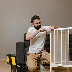 Man assembling white crib with screwdriver