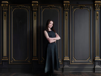 Woman posing confidently in a studio portrait against a black and gold ornate backdrop photographed in Lawrenceville, Georgia.