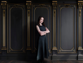 Woman posing confidently in a studio portrait against a black and gold ornate backdrop photographed in Lawrenceville, Georgia.