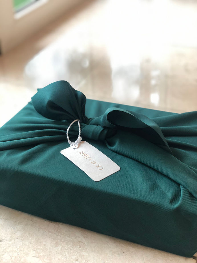 Gift box tied up with emerald green silk fabric and Jimmy Choo tag in a Japanese Furoshiki wrapping style.