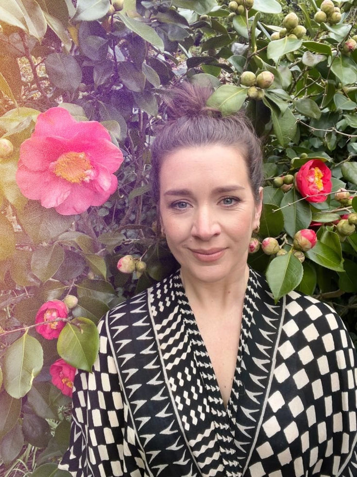 Rhiannon stands in front of a beautiful plant