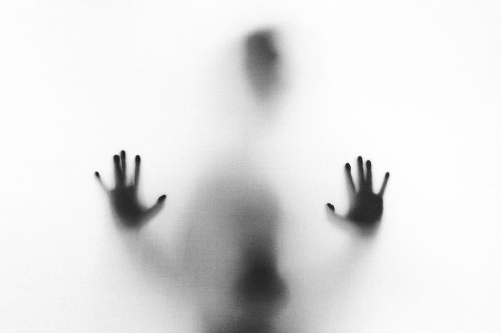 a very hazy picture of mostly white with shadows of a person with their hands pressed up against the surface