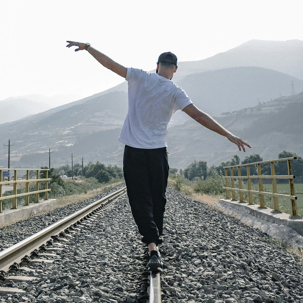 A man balancing himself as he walks along a railroad rail