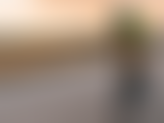 Cyclist in bright gear rides a black bike on an open road at sunset, with fields and mountains in the background. Mood is focused and intense.