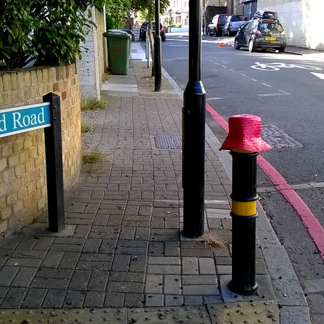 a straw hat on a bollard beside an old road