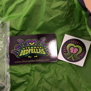 A closeup to Strange Bedfellas business card (left) and a sticker (right)