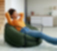 Rest And Relax Concept. Calm black woman sitting on bean bag, listening to music, audio bo