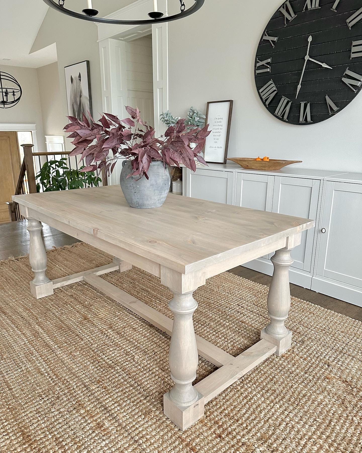 Rustic light wood console table with vase of burgundy leaves