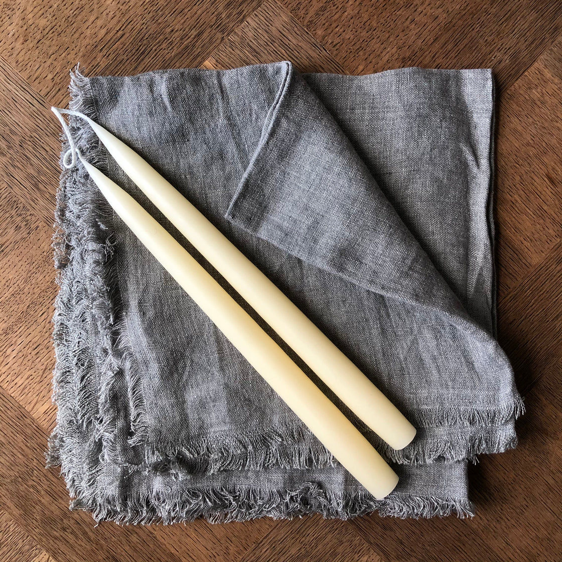 Two candles and gray linen napkin on a wooden table for decoration