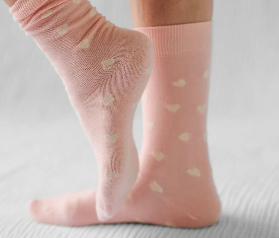 Miniature : Pink socks with white hearts. One foot raised, the other on the ground.