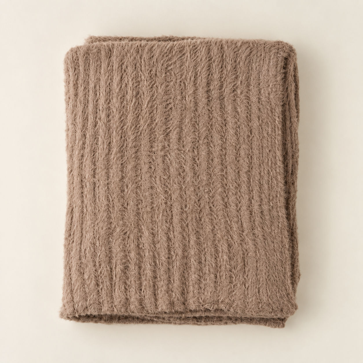 Folded taupe Snug Throw in Tuffet texture.