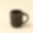 Black ceramic mug with a brown rim on a light yellow background.