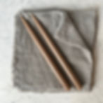 Two brown candles on a gray linen cloth, simple and elegant setting.