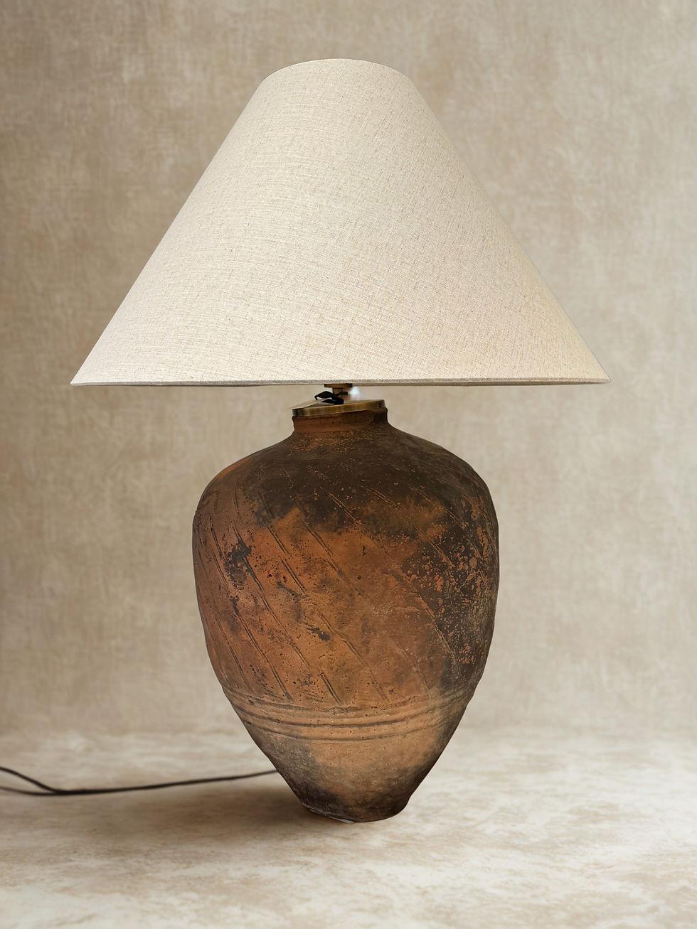 Rustic lamp with a beige shade on a brown pottery base, home decor.