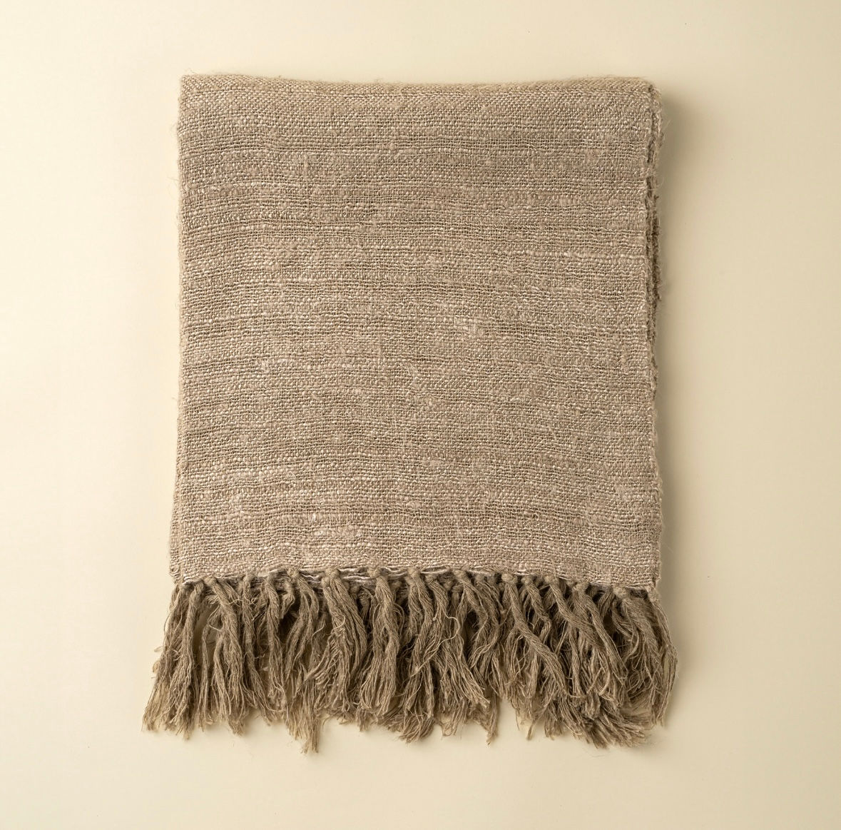 Folded brown woven blanket with fringe