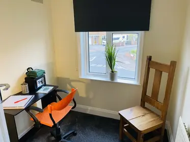 A clean, fresh and comfortable home office environment with chair, desk, and window.