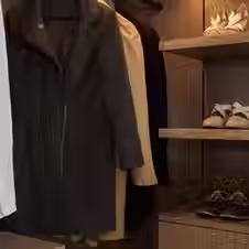 A wardrobe and open storage for clothes and shoes in a dark naturally grained wood.