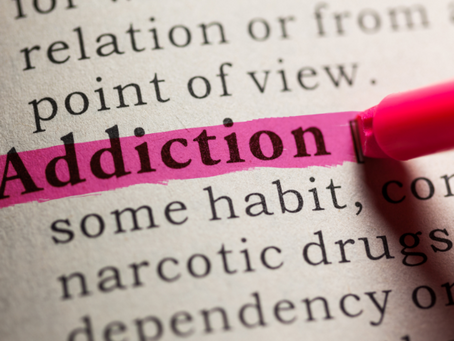 Close-up of a book page with Addiction highlighted in pink by a marker, creating a serious, focused mood.