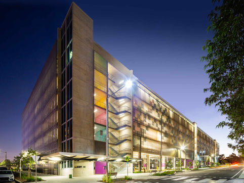 Edmondson Park Commuter Car Park at dusk showing multistorey building with award-winning design, exposed staircase, patterned illuminated facade.