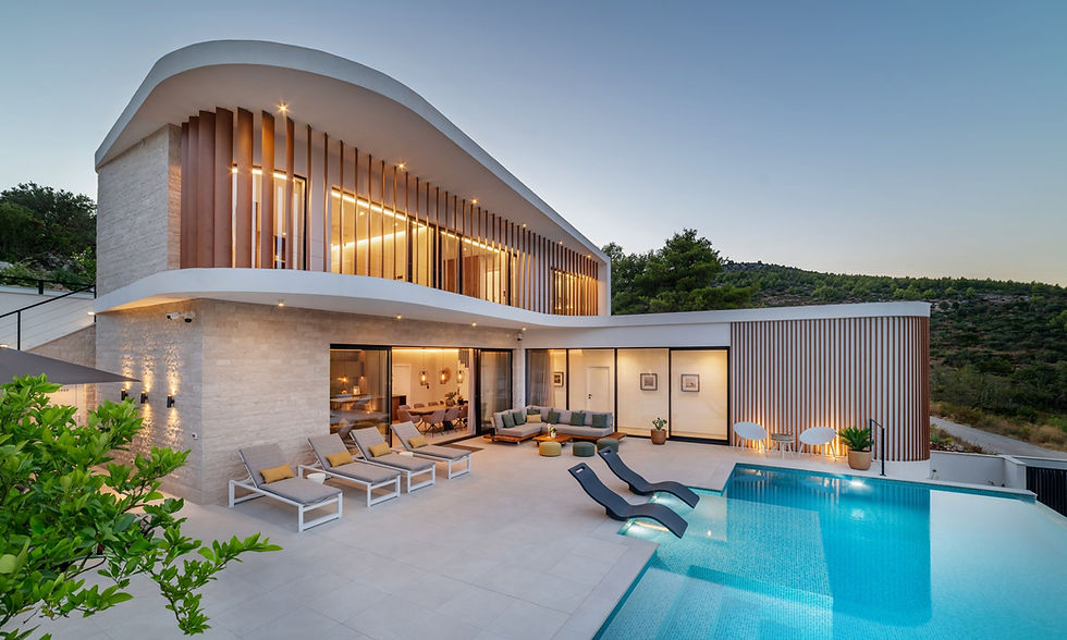 Villa Croatia - Modern luxury villa with curved roof, large windows, lounge chairs, timber louvers and timber slat detailing on the facade, and turquoise pool at dusk in a hillside setting with coastal beach views.