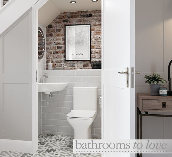 small toilet under the staircase, white, brick background, mirror, basin, artwork, tiled floor