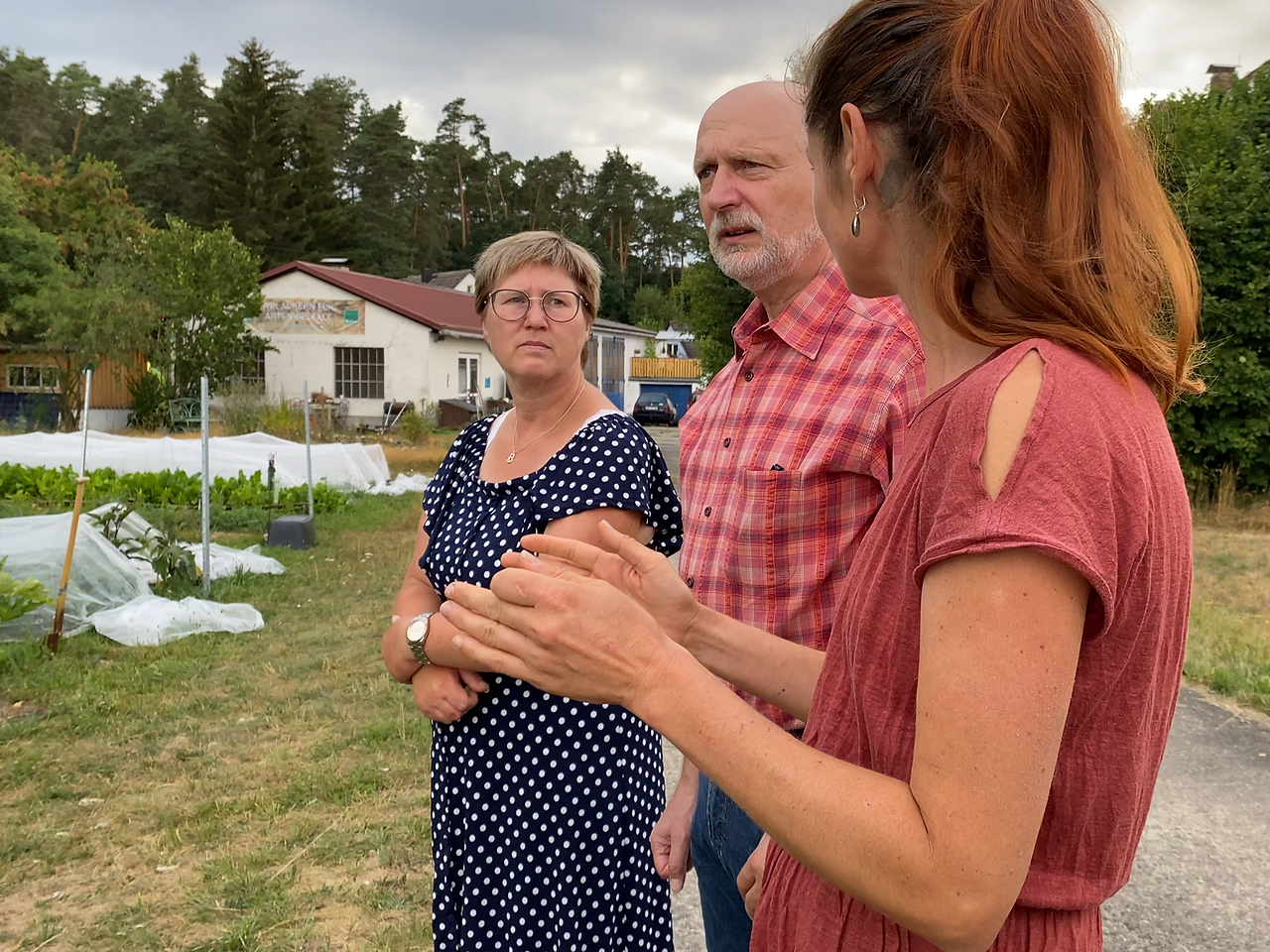 Zwei Frauen und ein Mann unterhalten sich vor einem Feld
