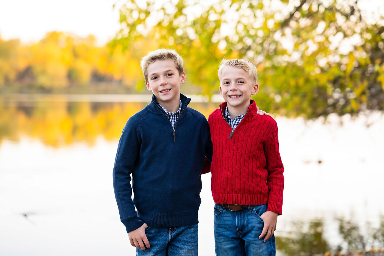 young brothers with arms around each other posing for a portrait on the banks of the fox river. 
