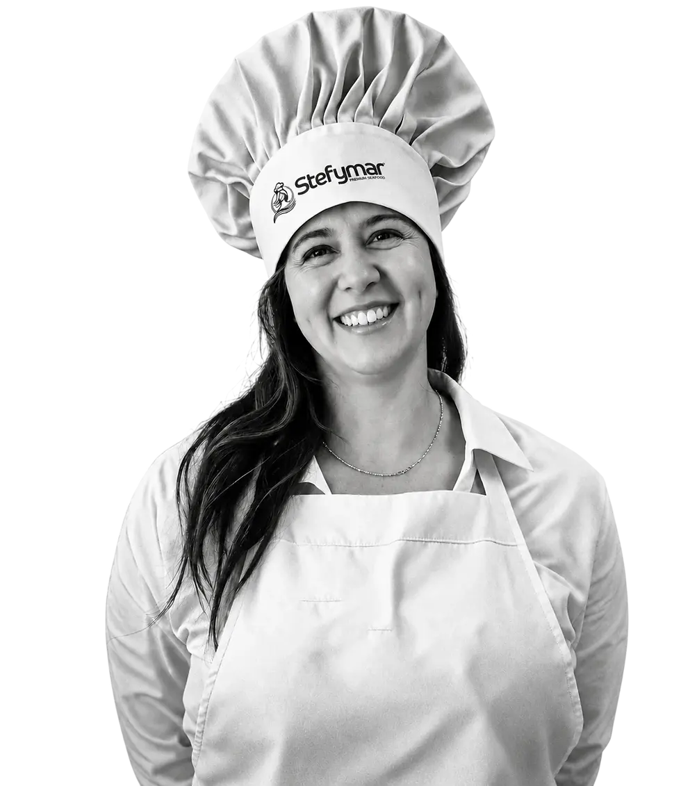 Studio photography of a woman in chef's attire, smiling professionally. The image conveys a friendly and welcoming atmosphere for culinary services.