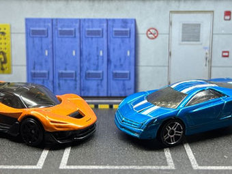 Two hot wheels diecast racing cars in a garage