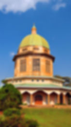 A view of Kampala with its dense buildings, green spaces, and Lake Victoria in the distance.