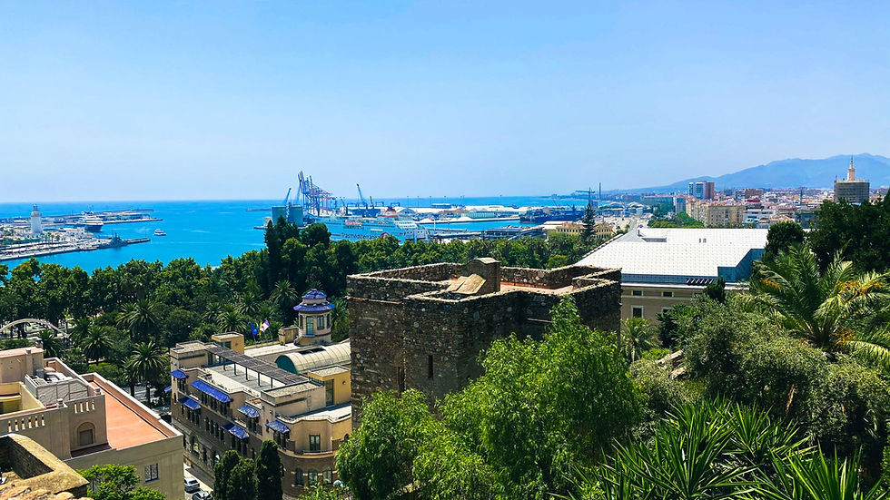 Scenic view of the port in Málaga, featuring boats, clear blue water, and the surrounding city skyline on a bright, sunny day.