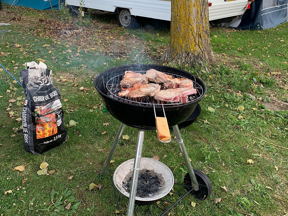 Des entrecôtes cuisant sur un barbecue dans un camping