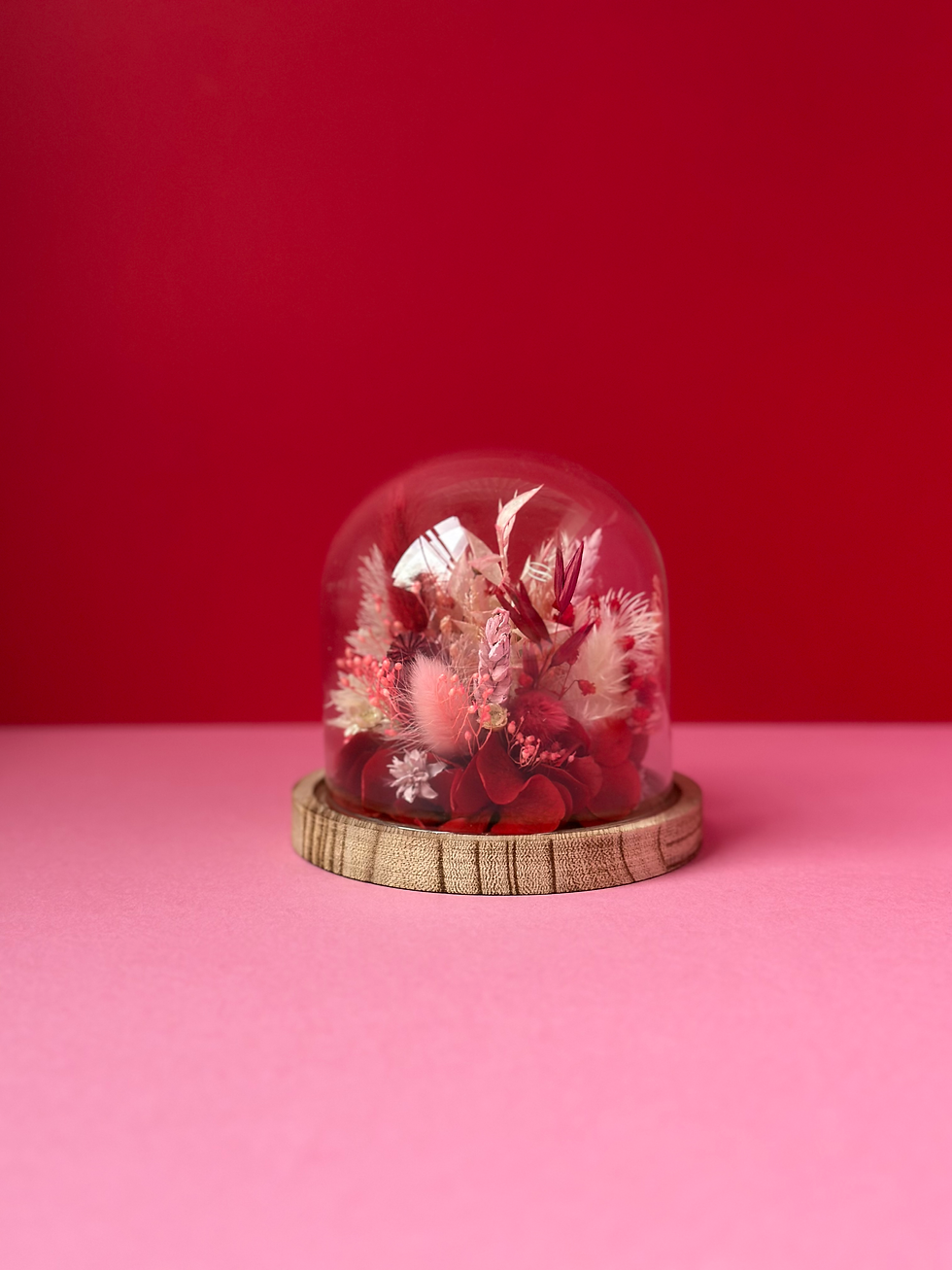 Cloche en verre avec socle en bois décoré de fleurs séchées rouge et rose pâle