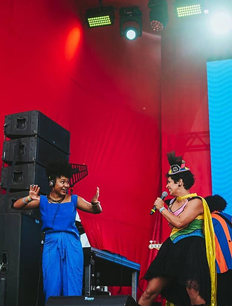 Intérprete de Libras no palco de um show, interagindo em Libras com uma cantora.