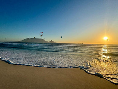 Watch breathtaking sunsets at Sunset Beach, Cape Town, with windsurfing and kitesurfing action framed by Table Mountain—an unforgettable experience for guests of this luxury villa.