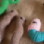 three Generation Soil handmade crochet worms, two brown, one blue with pink balaclava, one green