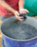 hands holding biochar in blue oil drum made for Generation soil in bristol