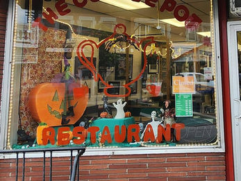 Restaurant window with Halloween decor: a jack-o'-lantern, ghosts, and witch hats. "The Coffee Pot Restaurant" in bold letters, "Closed" sign visible.