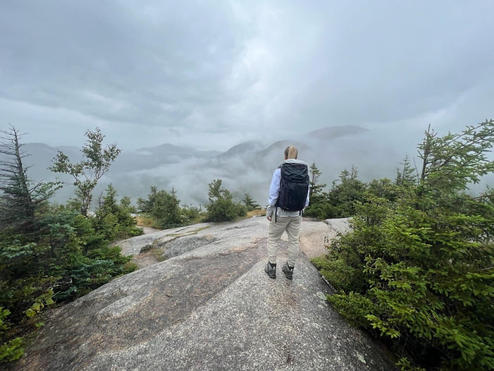 Hiker viewing cloudy mountain range from a peak