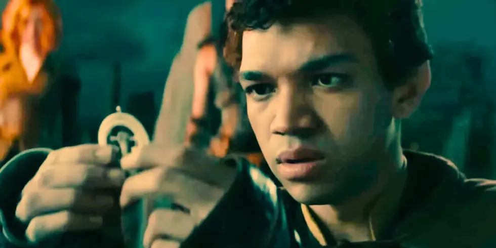 Simon Aumar interpretado por Justice Smith. Ele segura um artefato nas mãos enquanto olha intensamente.