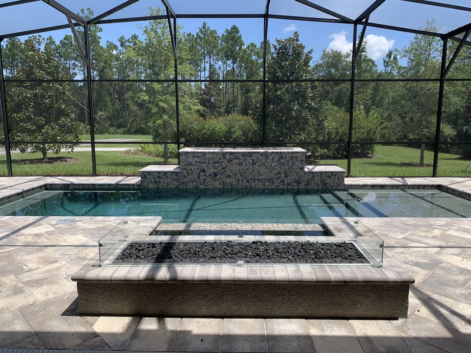 Screened pool with spillover wall and glass fire feature