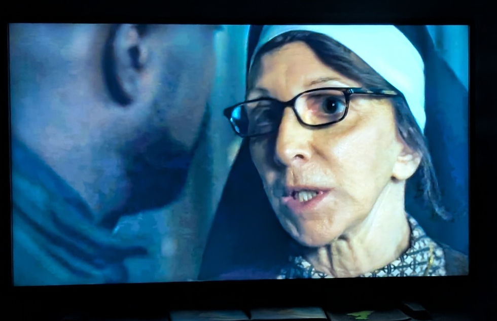 a nun with glasses wearing a traditional habit speaks to a man