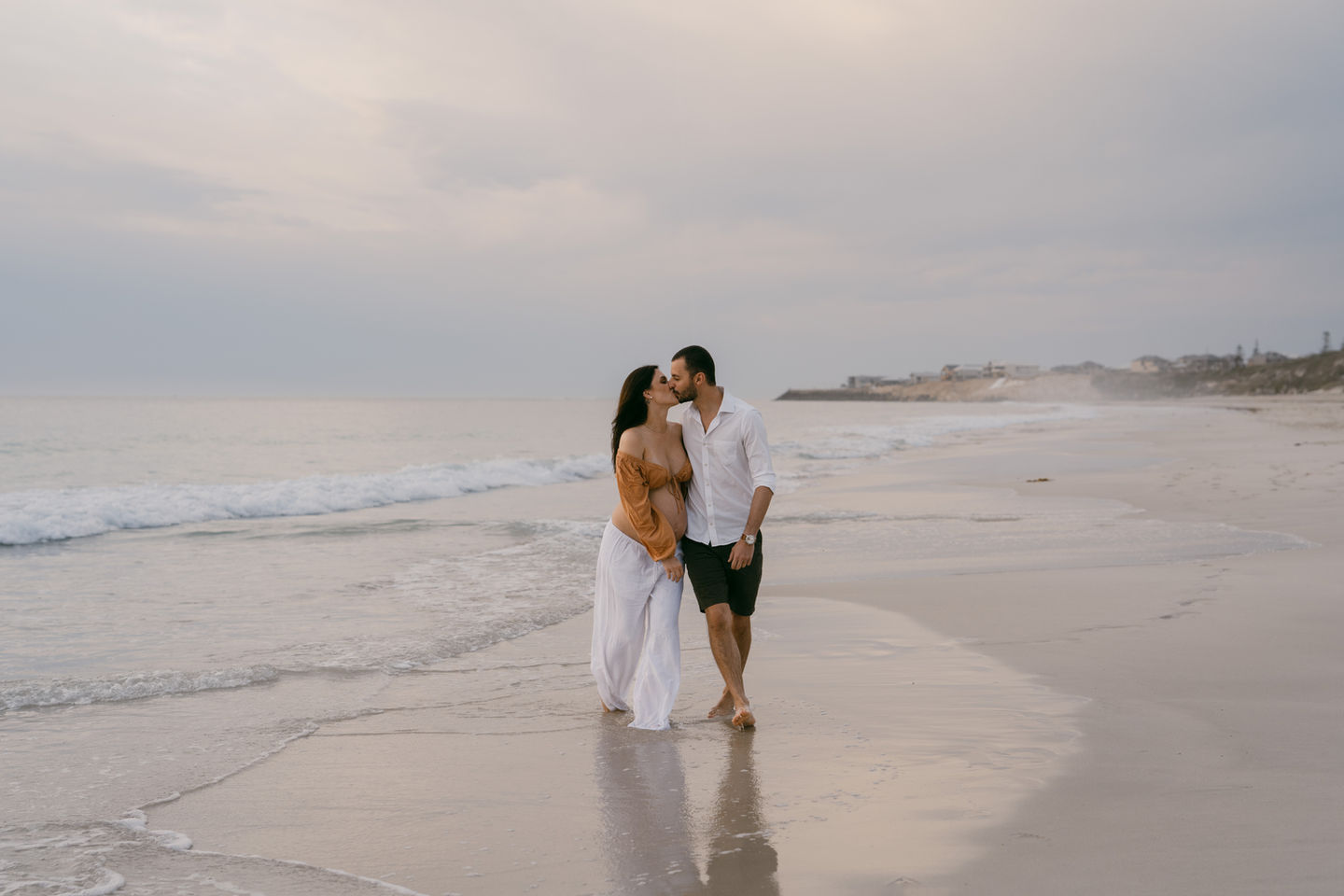 Expectant Mum and Dad walking along the shoreline in Perth
