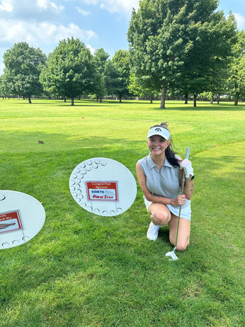 Woman in golf attire on course near Hole Sponsor signs