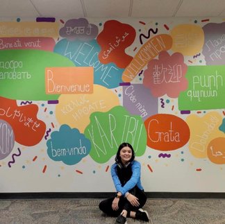Person by CLCL mural: 'Welcome' in many languages