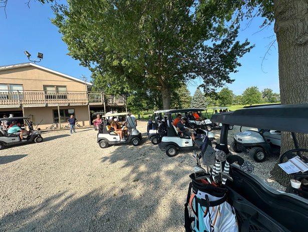 Golf event with people and carts outside clubhouse