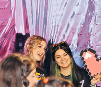 Two women laughing, holding a pixelated heart at an event