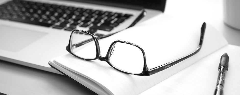 Glasses sitting on notebook next to open laptop