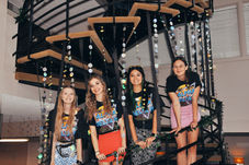 Four smiling women on festive spiral staircase