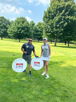 Man with trophy, woman with signs on golf course